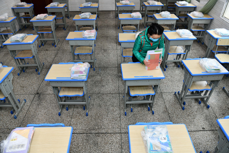 3月15日，在贵阳市云岩区第一小学初三年级集中教学点，老师为学生摆放和整理新课本。 新华社 图
