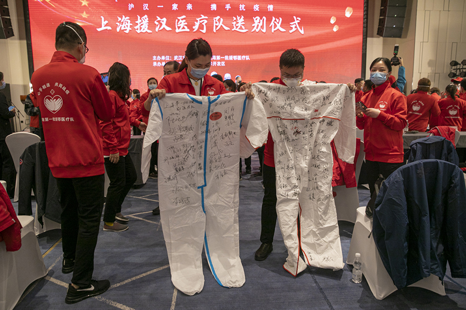 3月30日，武汉市东西湖区卓尔万豪，上海首批援汉医疗队的队员们在防护服上签名留念。