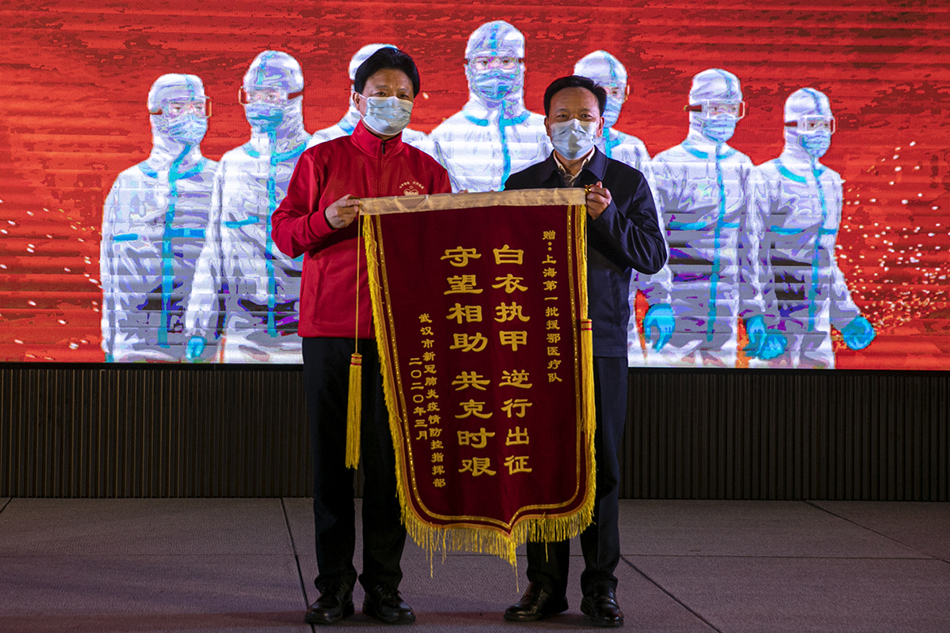 3月30日，武汉市东西湖区卓尔万豪，上海首批援汉医疗队队长郑军华（左）接过锦旗。