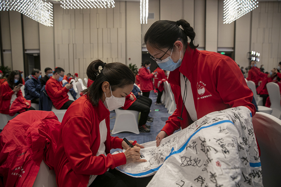 3月30日，武汉市东西湖区卓尔万豪，上海首批援汉医疗队的队员们在防护服上签名留念