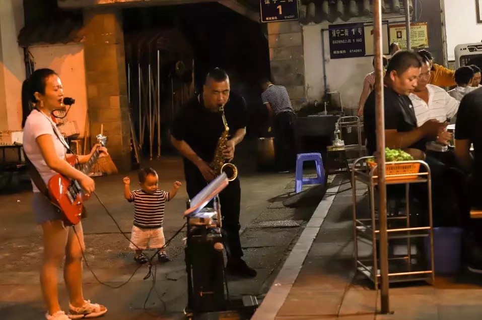 乐山夜市，火锅摊旁表演的街头艺人。