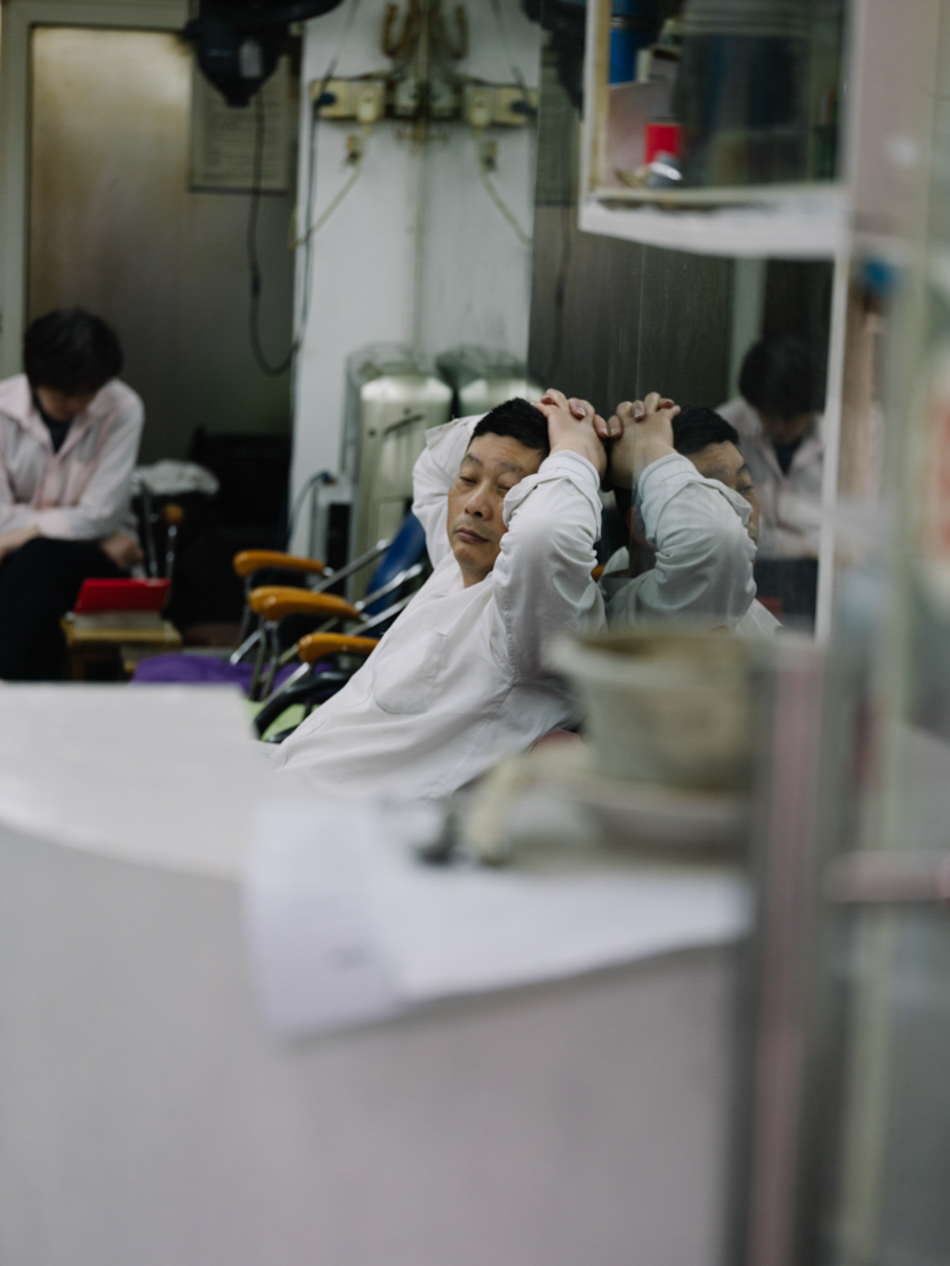 2020年4月16日晚,上海南昌路一家老式理发店顾客寥寥,技师靠着座椅