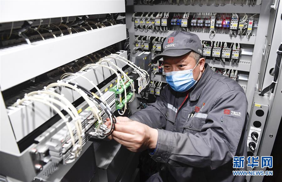 中车长春轨道客车股份有限公司首席操作师罗昭强在车间内对一列复兴号动车组列车进行调试作业(4月26日摄)。新华社记者 许畅 摄