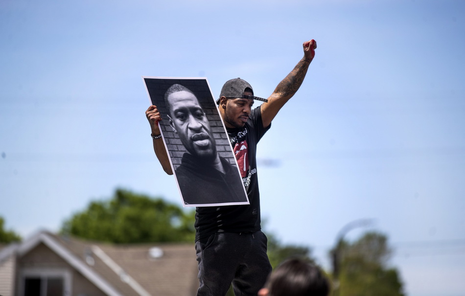 5月28日，在美国明尼阿波利斯，一名男子手举受害人乔治·弗洛伊德的遗像参加抗议活动。