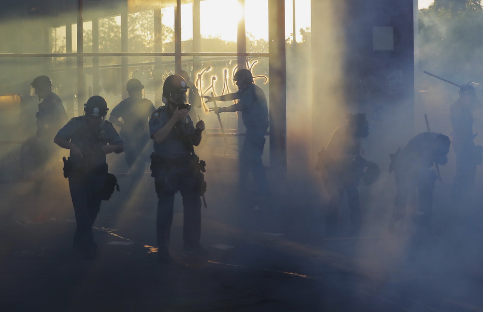 5月28日，在美国圣保罗市，警察穿过一段被烟雾笼罩的区域。