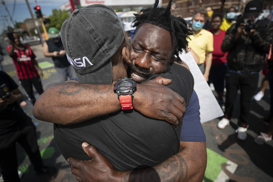 5月28日，在美国明尼阿波利斯，人们参加抗议活动时拥抱。