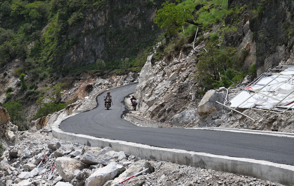 6月29日，阿布洛哈村村民骑着摩托车行驶在通村公路上。