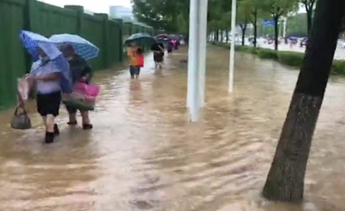 武汉暴雨市区渍水严重，有市民打赤脚涉水上班