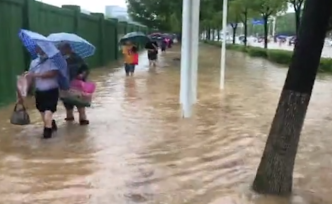武汉暴雨市区渍水严重，有市民打赤脚涉水上班