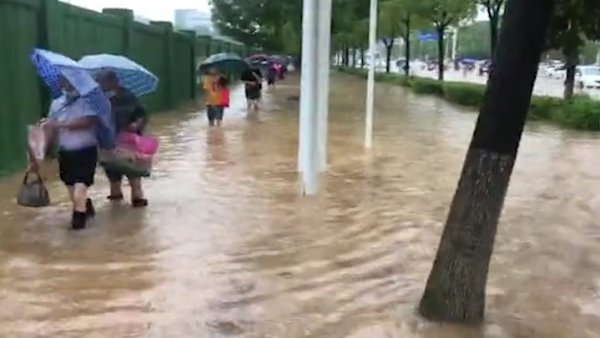 武汉暴雨市区渍水严重，有市民打赤脚涉水上班