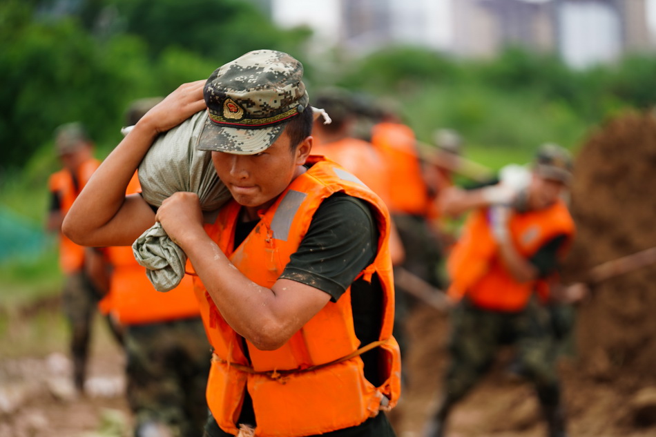 7月11日，武警战士在鄱阳县鄱阳镇江家岭村搬运沙袋。-