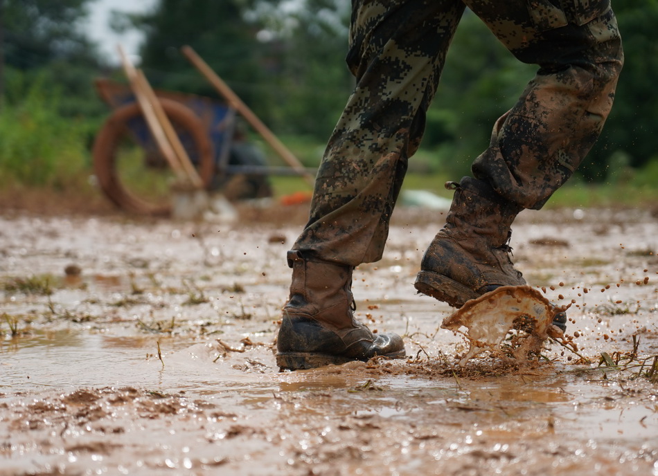 7月11日，在鄱阳县鄱阳镇江家岭村，一名武警战士在搬运沙袋时脚下溅起泥水。