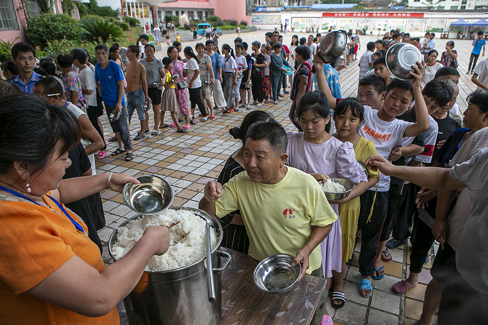2020年7月16日，江西省鄱阳县五一中心学校安置点，安置点内的受灾民众排队领取晚餐，今晚的晚餐包括辣椒炒肉,酸辣白菜和西红柿炒蛋。