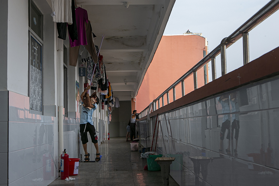 2020年7月16日，江西省鄱阳县五一中心学校安置点，男孩在走道里收衣服。