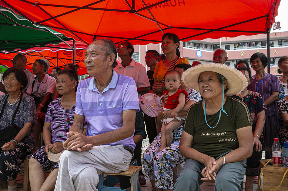 2020年7月16日，江西省鄱阳县五一中心学校安置点，受灾民众在遮阳伞下看赣剧。