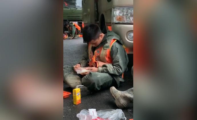 排除险情后坐路边吃饭，抗洪消防员手捧盒饭睡着了