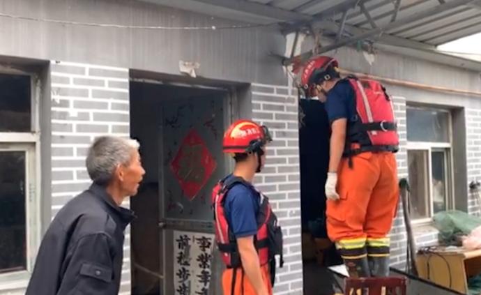 消防员在老人家中避雨，顺手修补漏雨屋顶