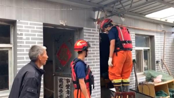 消防员在老人家中避雨，顺手修补漏雨屋顶