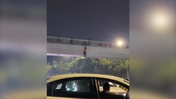 武汉一男子在天桥悬挂3分钟落下，路人喊面包车前往接住