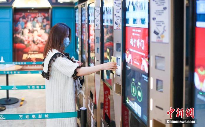 资料图:7月24日,观众在北京万达影城CBD店内自助扫码取票。中新网 图