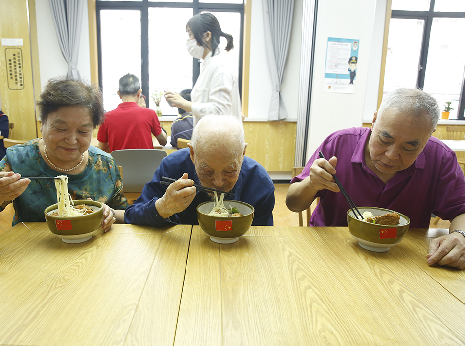 来自普陀区石泉路街道镇坪居民区106岁的李佩印老人（中间）正在和居民朋友一起吃国庆面。.jpg