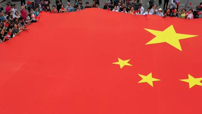 數千游客手動傳遞巨幅國旗,合唱祝福祖國